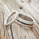 Shown here is a matching wedding band set featuring "Eterna" & "Rainier", laying together. "Eterna" is a stacking-style wedding band featuring an antler inlay. "Rainier" is a handcrafted wide wedding band featuring antler and ironwood inlays. Additional inlay options are available upon request. 