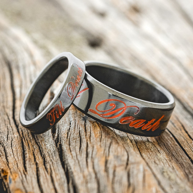 Shown here is "Till Death", a custom, handcrafted matching set of custom wedding bands with glow in the dark engravings, laying together. It can be customized to feature just about any engraved design you can dream up.
