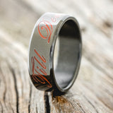 Shown here is "Till Death", a custom, handcrafted wedding band with a glow-in-the-dark engraving, upright facing left. It can be customized to feature just about any engraved design you can dream up.
