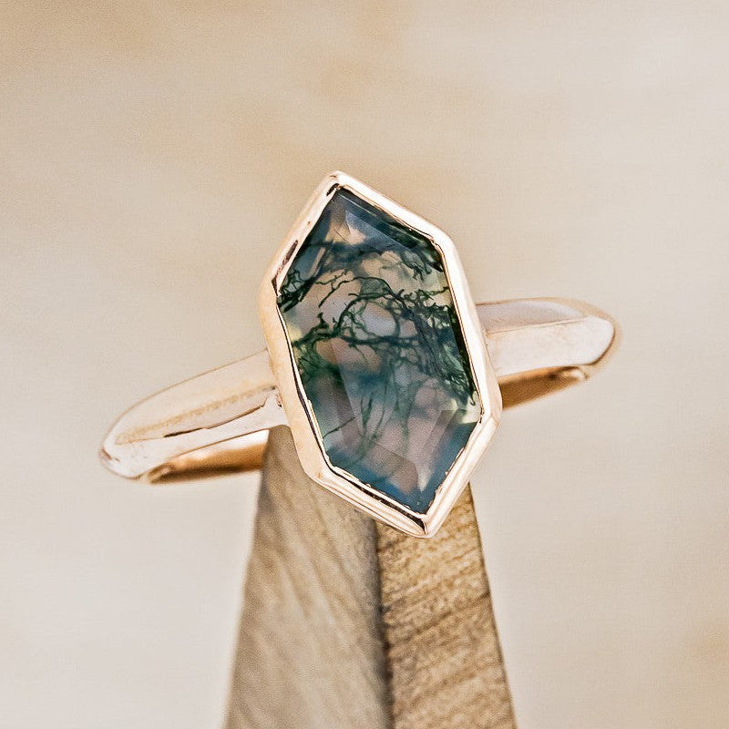Shown here is "Cora", a solitaire-style moss agate women's engagement ring, on stand front facing. Many other center stone options are available upon request.