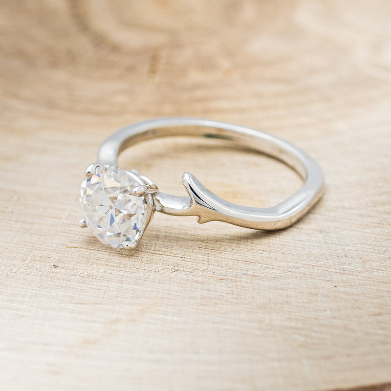Shown here is "Artemis", a moissanite women's engagement ring with an antler/branch style band, facing left. Many other center stone options are available upon request.