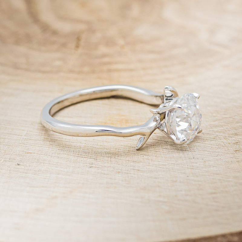 Shown here is "Artemis", a moissanite women's engagement ring with an antler/branch style band, facing right. Many other center stone options are available upon request.