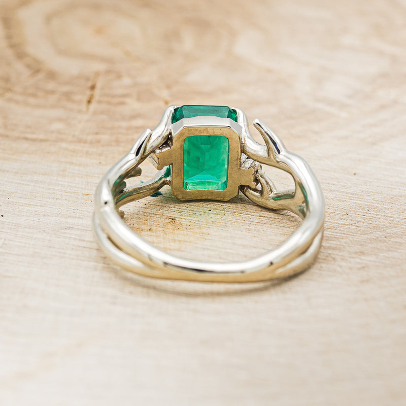 Shown here is "Artemis", an antler/branch-style lab-created emerald women's engagement ring with sapphire accents, back view. Many other center stone options are available upon request.