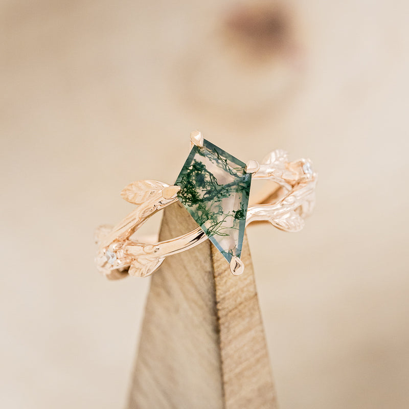 Shown here is "Artemis on the Vine", a branch-style moss agate women's engagement ring with diamond and leaf accents, on stand front facing. Many other center stone options are available upon request.  