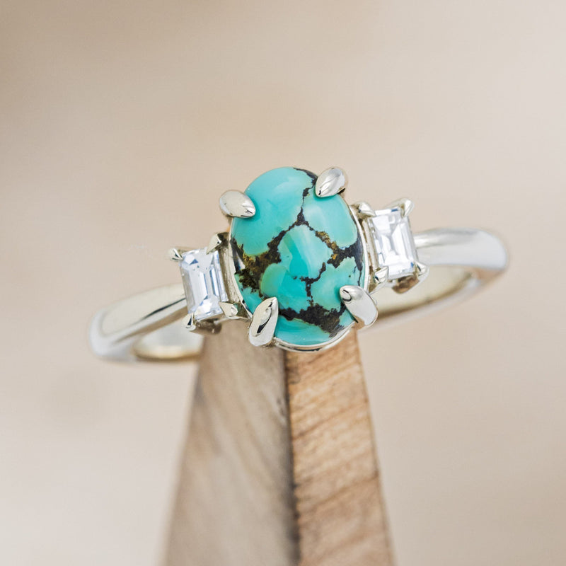 Shown here is "Presley", a turquoise women's engagement ring with baguette diamond accents, on stand front facing. Many other center stone options are available upon request. 
