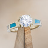 Shown here is "Fawn", an antler-style pronged moissanite women's engagement ring with antler and turquoise inlays, on stand front facing. Many other center stone options are available upon request.