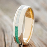 Shown here is "Four Corners", a custom, handcrafted men's wedding ring featuring 4 channels with antler, malachite, whiskey barrel oak and patina copper inlays on a 14K yellow gold lined band, upright facing left. Additional inlay options are available upon request.