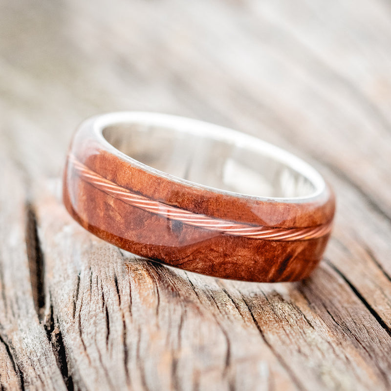 Shown here is "Remmy", a custom, handcrafted men's wedding ring featuring a redwood overlay and an offset twisted copper wire inlay, tilted left. Additional inlay options are available upon request.