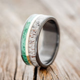 Shown here is "Raptor", a handcrafted men's wedding ring featuring two channels with malachite and antler inlays divided by a 14K yellow gold inlay, upright facing left. Additional inlay options are available upon request.