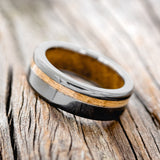 Shown here is "Vertigo", a handcrafted men's wedding ring featuring a whiskey barrel oak inlay and lining on a fire-treated black zirconium band, tilted left. Additional inlay and lining options are available upon request.