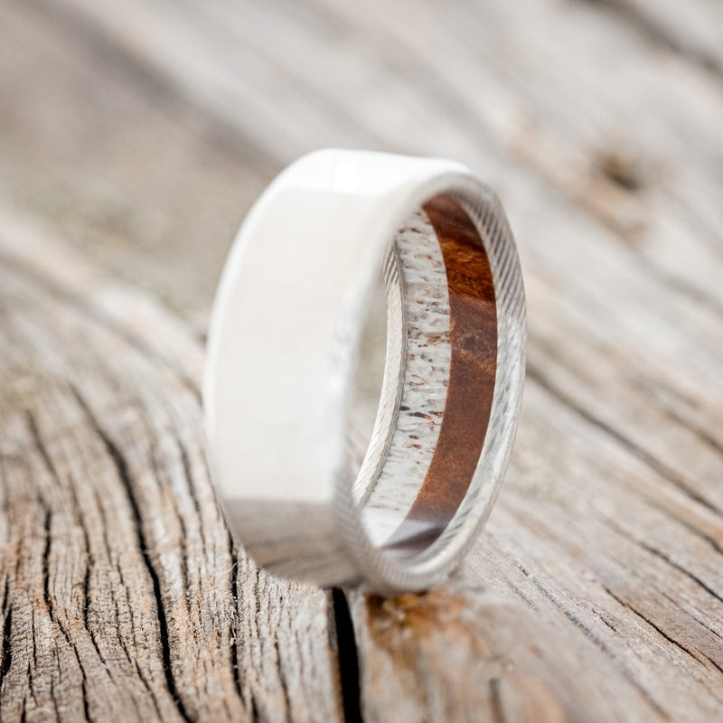 Shown here is a custom, handcrafted men's wedding ring featuring an elk antler and redwood lining, upright facing left. Additional lining options are available upon request.