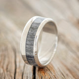 Shown here is "Tanner", a custom, handcrafted men's wedding ring featuring a grey birch wood inlay, upright facing left. Additional inlay options are available upon request.