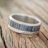 Shown here is "Tanner", a custom, handcrafted men's wedding ring featuring a grey birch wood inlay, tilted left. Additional inlay options are available upon request.