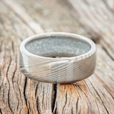 Shown here is a custom, handcrafted men's wedding ring featuring a hand-turned Damascus Steel wedding band lined with diamond dust, laying flat. Additional inlay options are available upon request.