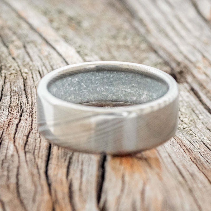 Shown here is a custom, handcrafted men's wedding ring featuring a hand-turned Damascus Steel wedding band lined with diamond dust, laying flat. Additional inlay options are available upon request.