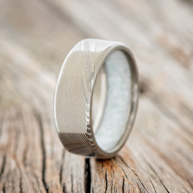 Shown here is a custom, handcrafted men's wedding ring featuring a hand-turned Damascus Steel wedding band lined with diamond dust, upright facing left. Additional inlay options are available upon request.