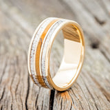 Shown here is "Rio", a custom, handcrafted men's wedding ring featuring 3 channels with elk antler and spalted maple inlays on a 14K yellow gold band, upright facing left. Additional inlay options are available upon request.