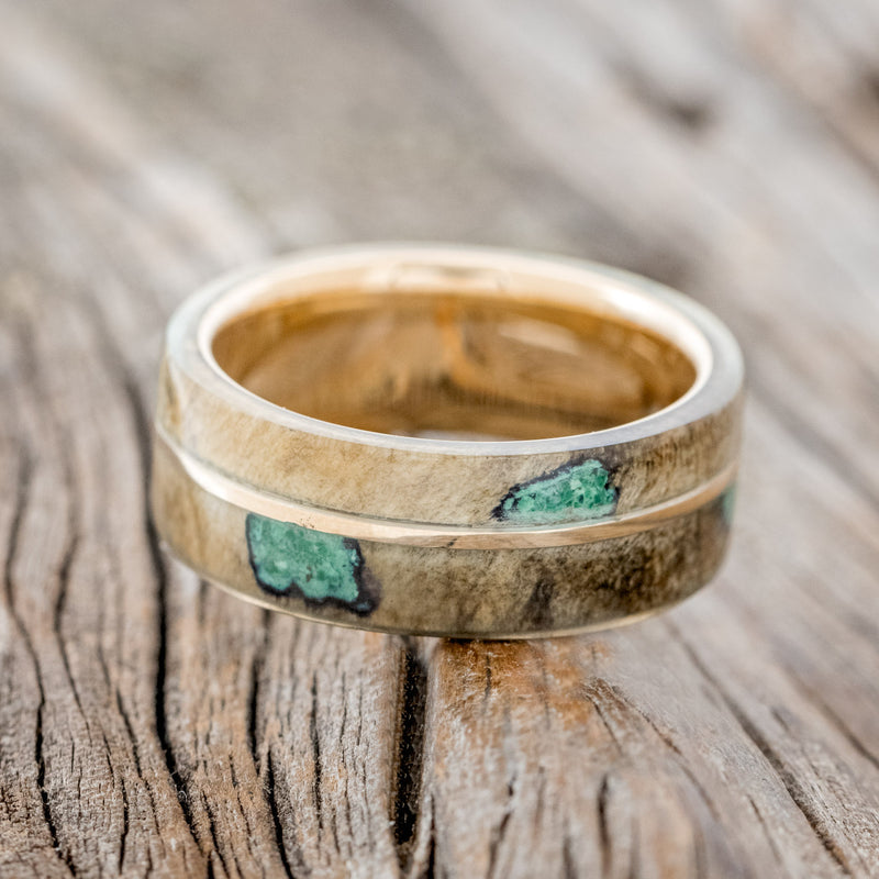 Shown here is "Golden", a custom, handcrafted men's wedding ring featuring a buckeye burl overlay with malachite inlays on a 14K gold band, laying flat. Additional inlay options are available upon request.
