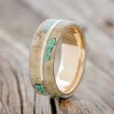 Shown here is "Golden", a custom, handcrafted men's wedding ring featuring a buckeye burl overlay with malachite inlays on a 14K gold band, upright facing left. Additional inlay options are available upon request.