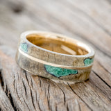 Shown here is "Golden", a custom, handcrafted men's wedding ring featuring a buckeye burl overlay with malachite inlays on a 14K gold band, tilted left. Additional inlay options are available upon request.