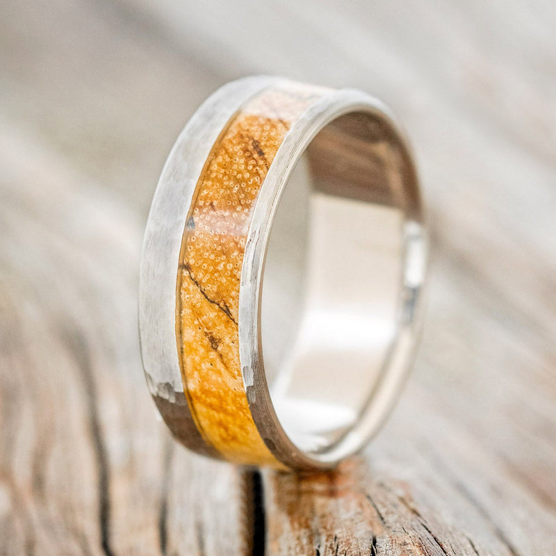 "Tanner" is a custom, handcrafted men's wedding ring featuring a spalted maple wood inlay with a hammered band, upright facing left. Additional inlay options are available upon request.