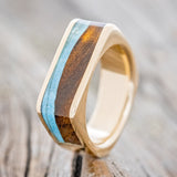 Shown here is "Mesa", a custom, handcrafted men's wedding band featuring a flat top 14K gold band with ironwood and turquoise inlays, upright facing left. Additional inlay options are available upon request.