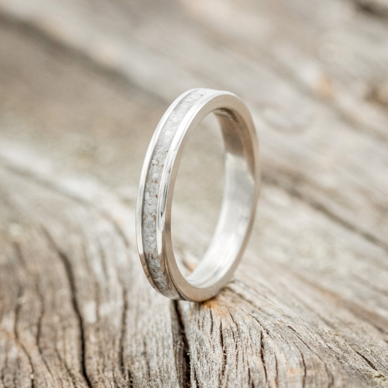 Shown here is "Eterna", a custom, handcrafted women's stacking band featuring an elk tooth ivory inlay on a titanium band, upright facing left. Additional inlay options are available upon request.