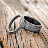 Shown here is a matching wedding band set featuring two black zirconium bands with a hammered finish, laying together.