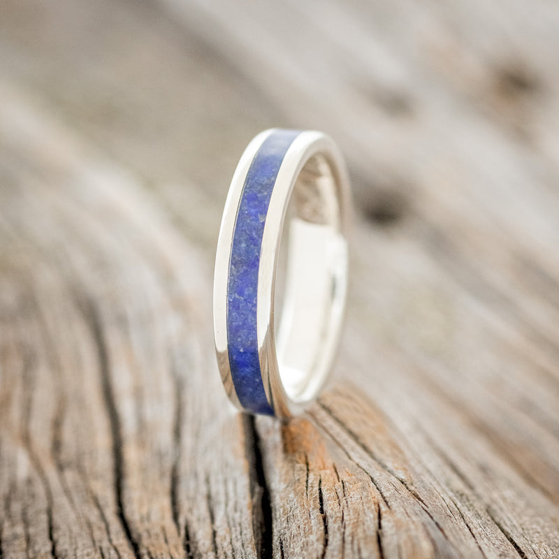 Shown here is "Perenna", a custom, handcrafted women's stacking band featuring a lapis lazuli inlay on a 14K gold band, upright facing left. Additional inlay options are available upon request.