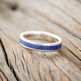 Shown here is "Perenna", a custom, handcrafted women's stacking band featuring a lapis lazuli inlay on a 14K gold band, tilted left. Additional inlay options are available upon request.