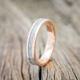 Shown here is "Perenna", a custom, handcrafted women's stacking band featuring a fire and ice opal inlay on a 14K gold band, upright facing left. Additional inlay options are available upon request.