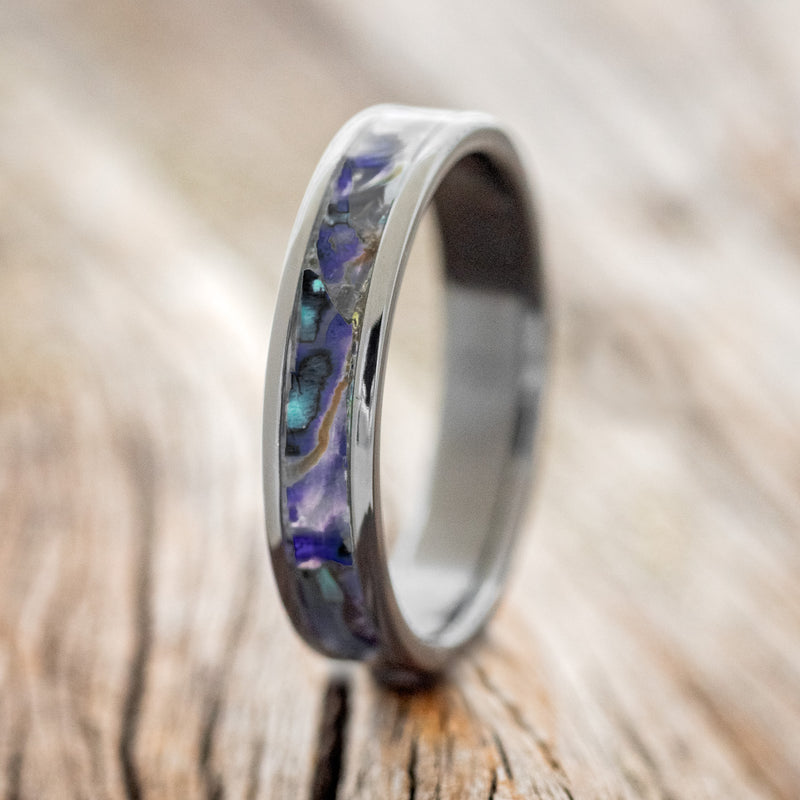 Shown here is "Perenna", a custom, handcrafted women's stacking band featuring a paua shell inlay on a fire-treated black zirconium band, upright facing left. Additional inlay options are available upon request.