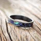 Shown here is "Perenna", a custom, handcrafted women's stacking band featuring a paua shell inlay on a fire-treated black zirconium band, tilted left. Additional inlay options are available upon request.