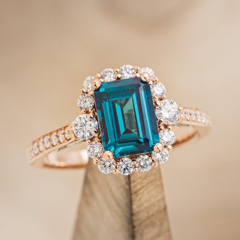 Shown here is "Ophelia", a lab-created alexandrite women's engagement ring with a diamond halo and diamond accents, on stand front facing. Many other center stone options are available upon request.