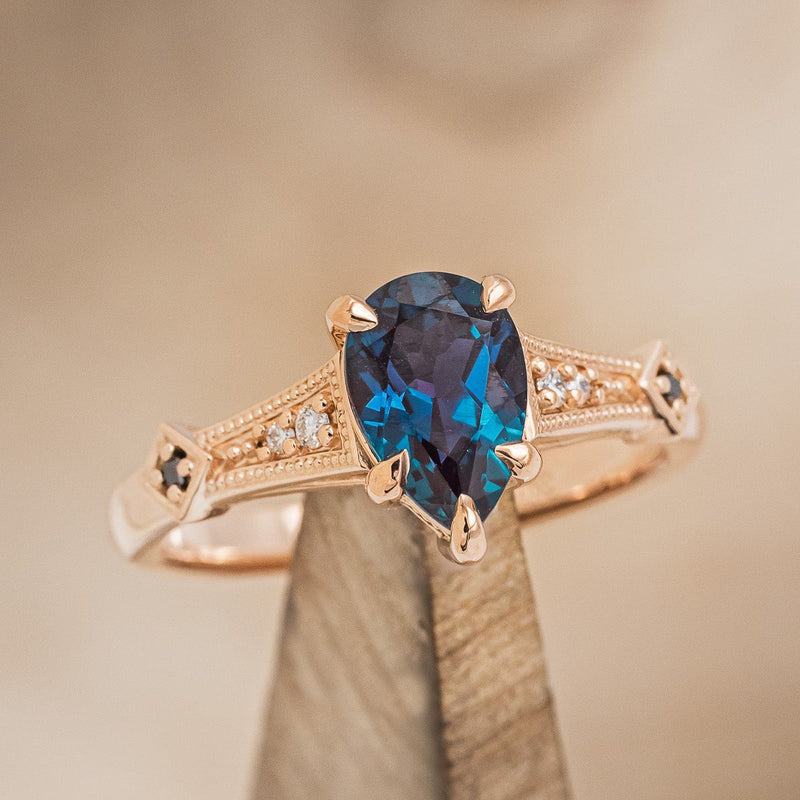 Shown here is "Annora", an accented-style lab-created alexandrite women's engagement ring with diamond and black diamond accents, on stand front facing. Many other center stone options and shapes are available upon request. 
