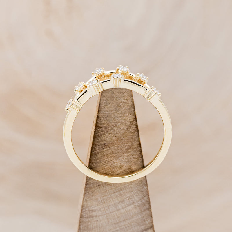 Shown here is "Zodiac", a custom, handcrafted women's stacker featuring a Capricorn constellation on a 14K gold band, side view on stand. People born between the dates of December 22nd – January 19th are a Capricorn.