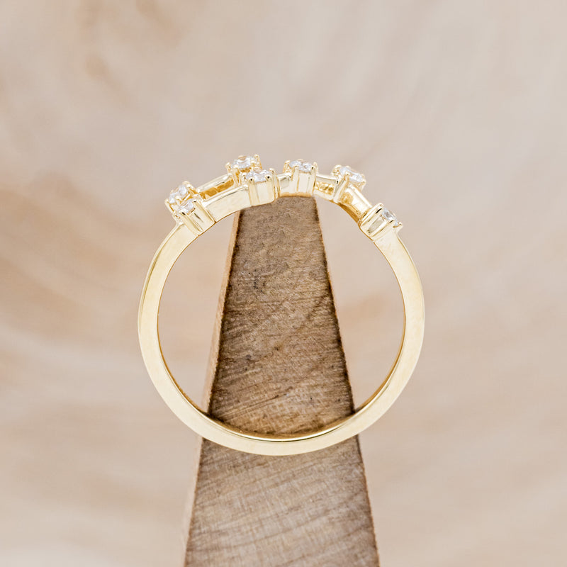 Shown here is "Zodiac", a custom, handcrafted women's stacker featuring a Leo constellation on a 14K gold band, side view on stand. People born between the dates of July 23rd – August 22nd are a Leo.