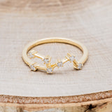 Shown here is "Zodiac", a custom, handcrafted women's stacker featuring a Leo constellation on a 14K gold band, front facing. People born between the dates of July 23rd – August 22nd are a Leo.
