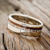 Shown here is "Castor", a custom, handcrafted men's wedding ring featuring ai ironwood and antler inlay on a 14K gold band, tilted left. Additional inlay options are available upon request.