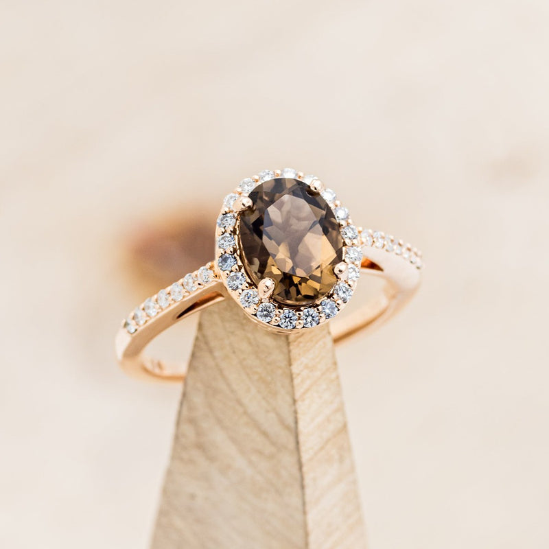 Shown here is "Diana", an oval smoky quartz women's engagement ring with a diamond halo and diamond accents, on stand front facing. Many other center stone options are available upon request.