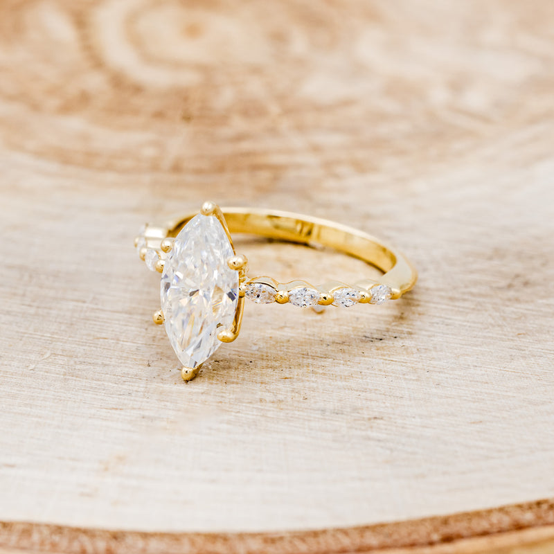 Shown here is "Romy", a marquise moissanite women's engagement ring with diamond accents, facing left. Many other center stone options are available upon request.