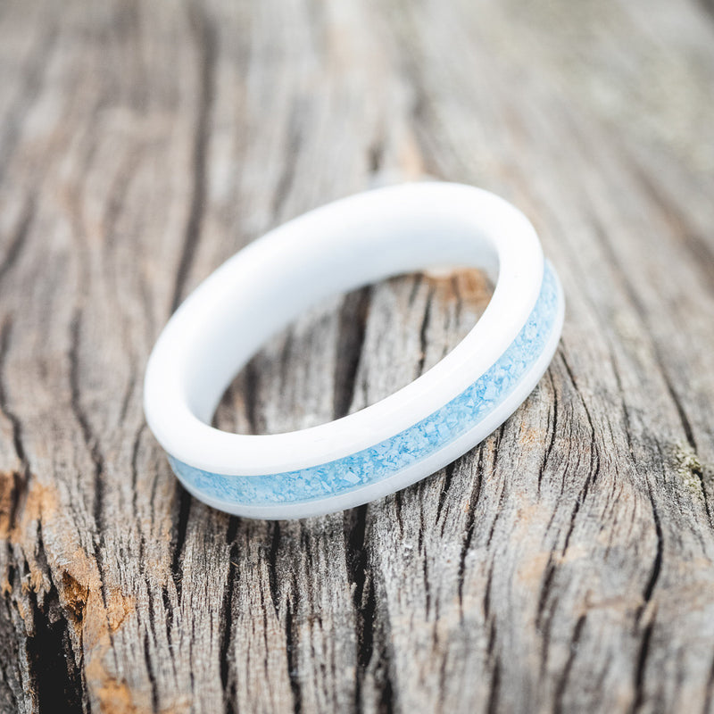 Shown here is "Perenna", a custom, handcrafted women's stacking band featuring a turquoise inlay on a white ceramic band, tilted right. Additional inlay options are available upon request.