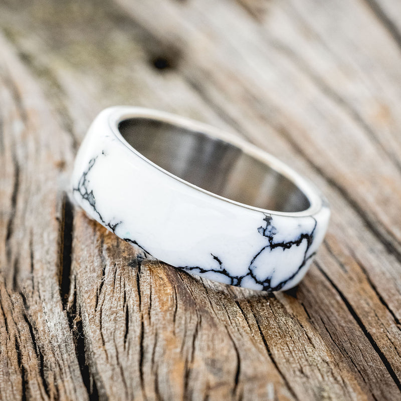 Shown here is "Haven", a custom, handcrafted men's wedding ring featuring a white turquoise TruStone overlay on a titanium band, tilted left. Additional overlay options are available upon request.