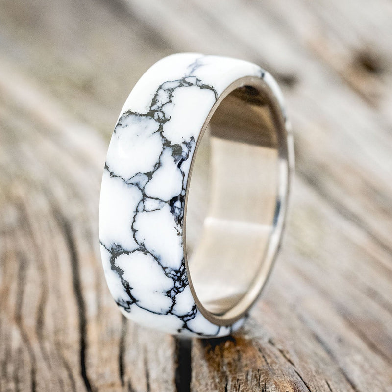 Shown here is "Haven", a custom, handcrafted men's wedding ring featuring a white turquoise TruStone overlay on a titanium band, upright facing left. Additional overlay options are available upon request.