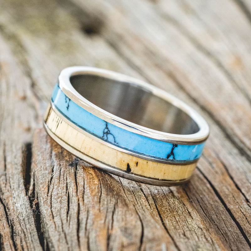 Shown here is "Dyad", a custom, handcrafted men's wedding ring featuring 2 channels with spalted maple wood and turquoise with black matrix TruStone inlays, tilted left. Additional inlay options are available upon request.