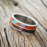 Shown here is "Dyad", a custom, handcrafted men's wedding ring featuring 2 channels with koa wood and Sonora sunset TruStone inlays, tilted left. Additional inlay options are available upon request.