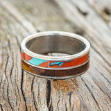 Shown here is "Dyad", a custom, handcrafted men's wedding ring featuring 2 channels with koa wood and Sonora sunset TruStone inlays, laying flat. Additional inlay options are available upon request.