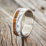 Shown here is "Dyad", a custom, handcrafted men's wedding ring featuring 2 channels with ironwood and white turquoise TruStone inlays, upright facing left. Additional inlay options are available upon request.