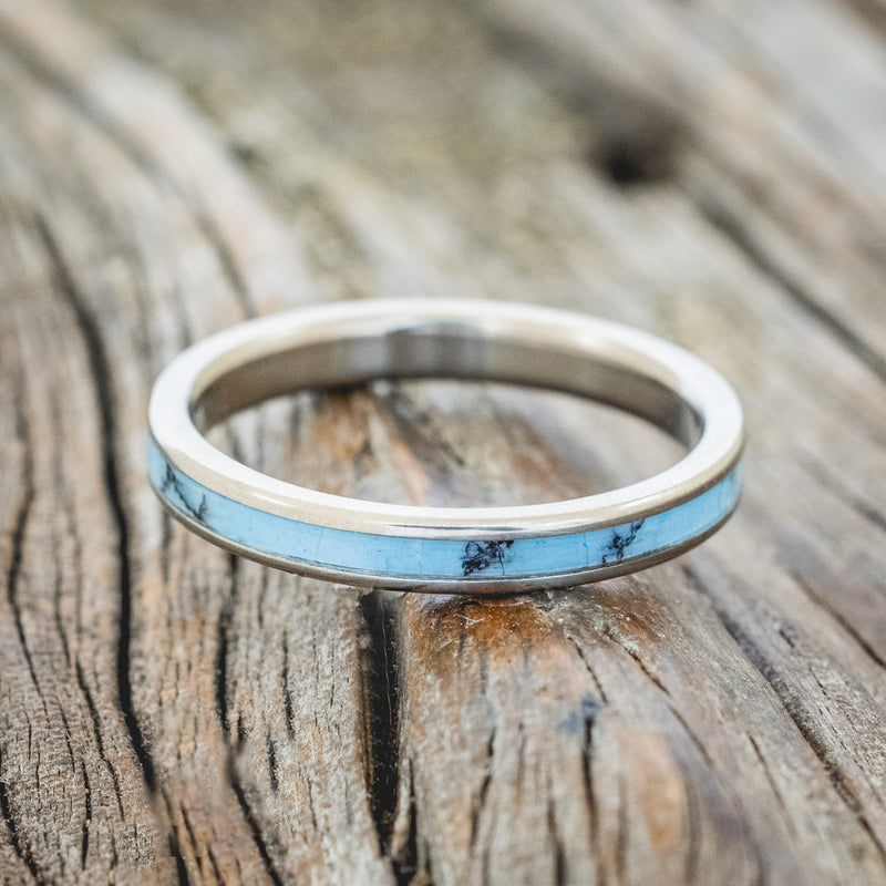 Shown here is "Eterna", a custom, handcrafted women's stacking band featuring a turquoise and black matrix TruStone inlay, laying flat. Additional inlay options are available upon request.