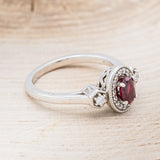 Shown here is "Amelia", a vintage-style lab-created ruby women's engagement ring with a diamond halo and diamond accents, facing right. Many other center stone options are available upon request.